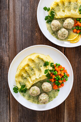 Wall Mural - Boiled meatballs in dill sauce with mashed potatoes and boiled carrot and green peas on wooden table	