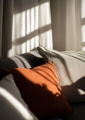 Close-up of a couch with two pillows on it. the pillows are orange and beige in color and are placed on the armrests of the couch.