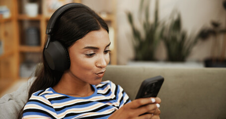 Aufkleber - Headphones, typing and woman with phone on sofa for social media, online subscription and music. Happy, chill and girl on smartphone listening to audio, playlist and podcast to relax in living room
