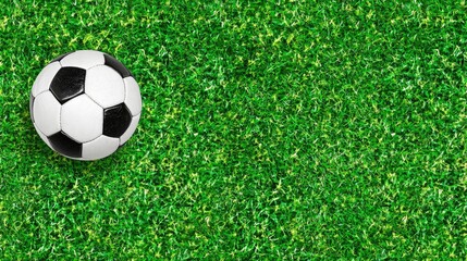 Poster - Flat lay of a black and white soccer ball on a smooth green grass background, top-down shot, no people