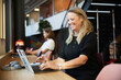 © Johnér - Smiling blond businesswoman working on laptop at desk in office