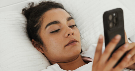 Leinwandbilder - Woman, phone and texting on bed in home, contact or wake up with notification in morning. Girl, smartphone and relax with mobile app, chat and reading post on social network in bedroom at apartment