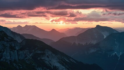 Wall Mural - Breathtaking sunset illuminating mountain peaks with vibrant pink and orange hues against distant ranges and dramatic cloud formations.