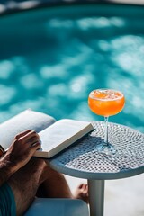 Wall Mural - a person sitting by the pool with an exotic cocktail, reading a book on their side table