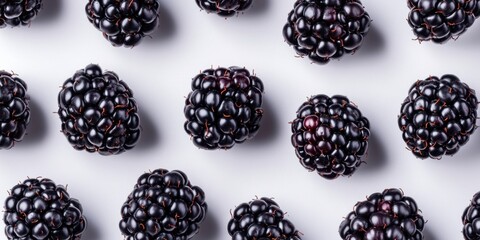Poster - Juicy ripe blackberries scattered on a light gray background with glossy surfaces and rich dark purple hues creating a vibrant and appealing display