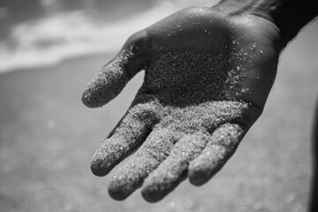 Wall Mural - A person stands on the beach, holding sand in their hand