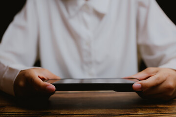 Poster - Person Holding Tablet Computer on Wooden Table in Dim Lighting