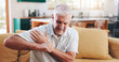 © peopleimages.com - Home, shoulder pain and senior man on sofa, broken and pressure in living room. Pensioner, apartment or mature person on couch, inflammation or joint injury in lounge, stress and bruise with burnout