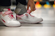 © juraj - Close-up of hands fastening velcro strap on child's white shoe with pink laces in a shoe store