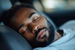 © A Damani - African american man sleeping in a car, resting head on wheel