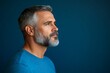 © Saxena - Profile portrait of middle-aged bearded man in blue t-shirt over blue studio background, copy space. Side view of handsome confident man posing on blue, standing straight and looking