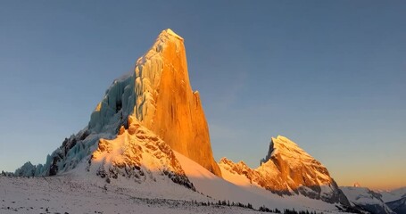 Poster - Snowy Mountain Peak Illuminated By Setting Sun with Blue Sky Background