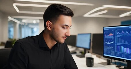 Aufkleber - Young Man in Black Shirt with Charts on a Computer Screen and a Mug in Office