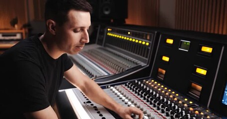 Poster - Man In Black Shirt Using A Mixing Console In A Studio Setting With Brown Wood Background and Equipment
