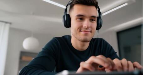 Poster - Happy Man Wearing Headphones Typing On Laptop At Desk In Office Setting With White Background