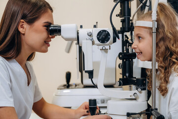 Wall Mural - View from the side. Little girl at the ophthalmologist clinic with doctor