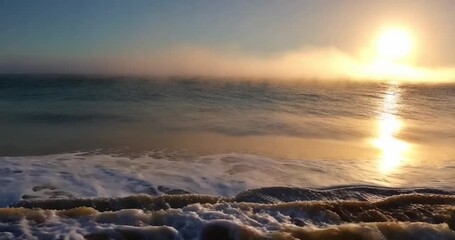 Poster - A breathtaking seascape showing frozen ocean water and a setting sun, captured in early morning. The sky is light blue, the water is blue and the sun is shining