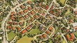 © achmad - Aerial view of a quaint town with red-roofed houses, green spaces, and winding roads.