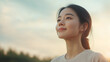 © NaphakStudio - Asian woman with warm smile, surrounded by greenery, exuding happiness and tranquility.