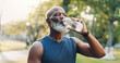 © peopleimages.com - Exercise, senior man and drinking water at park for fitness break, hydration or recovery from running. Detox, black person and liquid bottle for refresh, cardio workout or marathon training in nature