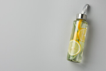 Wall Mural - Lemon water with cucumber in bottle on light grey background, top view. Space for text