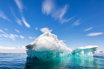 Wall Mural - glacial blue iceberg and sky background. turquoise underside of a snow covered iceberg in svalbard, 