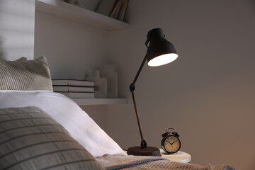 Wall Mural - Glowing night lamp and alarm clock on bedside table indoors