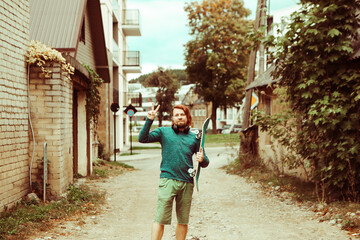 yong redharied man stand on the road with skateboard and headphones and showing peace  gesture