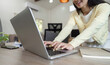 © wichayada - Business professional typing on laptop while reviewing documents at home