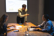 © Wavebreak Media - Business meeting at night, diverse team discussing digital solutions, charts on screen, at office