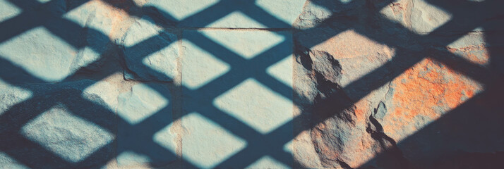 Poster - Forged metal grid shadows on rough stone wall – architectural texture study