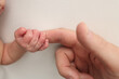 © Vad-Len - Close-up little hand of child and palm of mother and father. The newborn baby has a firm grip on the parent's finger after birth. A newborn holds on to mom's, dad's finger.