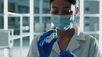 Poster - Professional scientist performing precise viral sample examination, wearing protective mask and gloves while carefully handling research vial inside laboratory setting