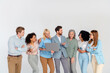© deagreez - Group of diverse colleagues discussing ideas while using a laptop in a professional business meeting on a neutral grey background