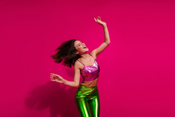 Wall Mural - Stylish young woman dancing in vibrant outfit against vivid magenta background, radiating joy and energy