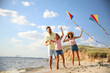 © New Africa - Happy parents and their child playing with kites on beach near sea. Spending time in nature