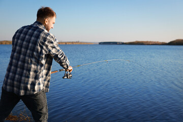 Wall Mural - Fisherman with rod fishing at riverside. Recreational activity