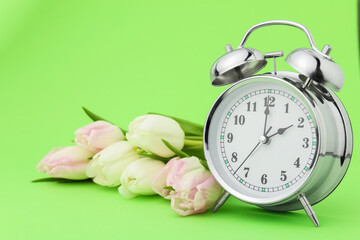 Poster - Spring time. Alarm clock and beautiful tulips on green background
