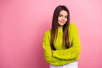 Wall Mural - Stylish young woman wearing a vibrant yellow sweater poses confidently against a soft pink background exuding charm and positive energy.