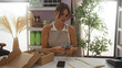 © Krakenimages.com - Woman counting money in home decor store surrounded by plants and merchandise, illustrating a business transaction in a modern retail setting.