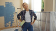 © Krakenimages.com - Woman painting indoors with roller smiling in living room during renovation process showcasing attractive young lifestyle in contemporary new apartment