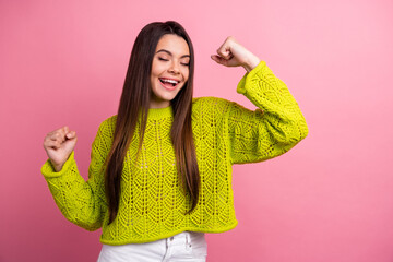 Wall Mural - Cheerful Young Woman in Vibrant Green Sweater Posing Joyfully Against a Bright Pink Background