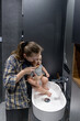 © volody10 - A woman with her baby brushes her teeth while holding a baby in hands in the bathroom