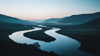 Wall Mural - Serpentine river winding through misty valley at dawn.