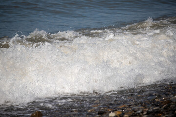 Seashore, small stones, sea wave. Marine background.