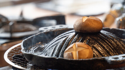 A cast iron pan with two baked bread rolls on top, surrounded by steam, showcasing a cozy cooking scene.