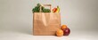 © sofia - Brown paper bag filled with groceries, fruits, and vegetables against a plain background for healthy eating promotion
