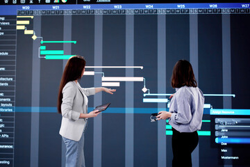 Poster - The young woman updates Gantt chart on her office computer
