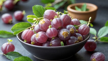 Poster - Fresh ripe organic gooseberries in a bowl with green leaves on a dark stone background. Soft focus on fruits with a rustic style.