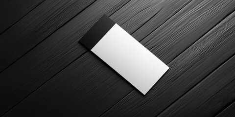 Poster - Minimalist mockup of a business card on a black wooden background featuring a black and white gradient design positioned centrally, top-down view